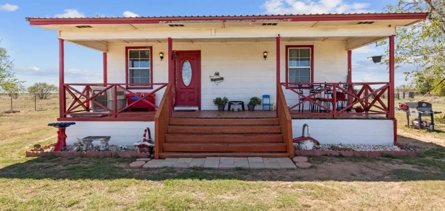StarHorn Ranch farmhouse with its red-trimmed front porch under a big Texas sky